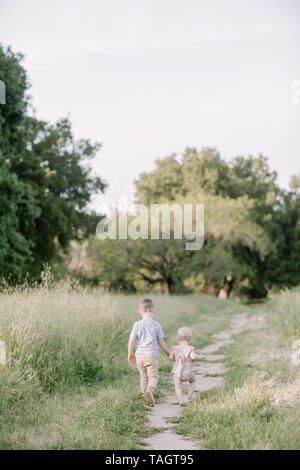 big brother and baby sister hug in a field Stock Photo