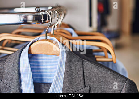 Mens suits and formal shirts on wooden hangers in a clothes store Stock Photo
