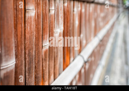 Kyoto, Japan residential area with closeup of bamboo wooden fence with red orange brown color by sidewalk Stock Photo