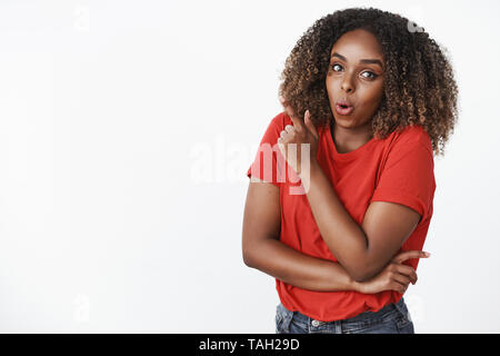 Wow interesting. Portrait of amused and surprised attractive young 25s african-american woman in red t-shirt folding lips in wonder and amazement Stock Photo