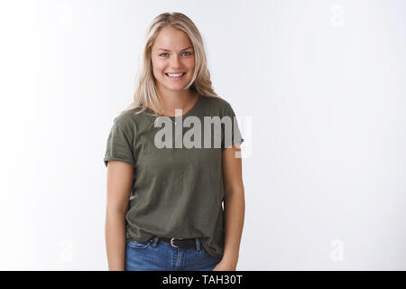 Happy joyful young european blond female in olive t-shirt feeling excited and carefree smiling broadly delighted with great quality service grinning Stock Photo
