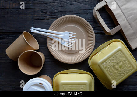 Disposable takeaway food boxes and tableware on dark wooden background. Nature friendly kitchen utensil. Stock Photo