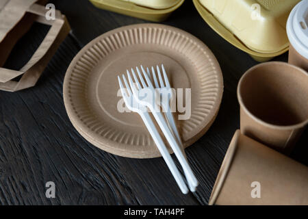 Disposable takeaway food boxes and tableware on dark wooden background. Nature friendly kitchen utensil. Stock Photo