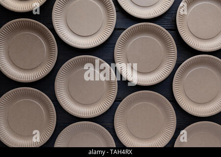 Paper disposable plate pattern on dark wooden background. Summer party, kitchen cutlery Stock Photo