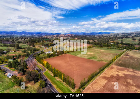 Square plowed cultivated farmland fields and paddocks of horse stables in Blandford town of upper Hunter valley near Scone - elevated aerial view. Stock Photo