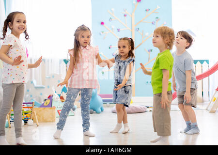 Happy children having fun dancing indoors in a sunny room at day care or entertainment center Stock Photo