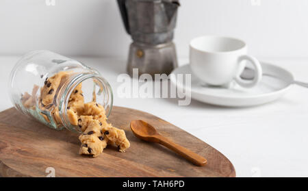A serving of homemade cookie dough on a wooden table, with a wooden spoon. With coffee in the background. Stock Photo