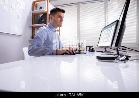 Side View Of Businessman's Hand Analyzing Data On Computer Over Desk Stock Photo