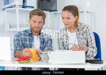 coworkers using multimeter to test electrical appliance Stock Photo