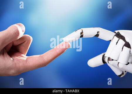 Robot Touching Man's Index Finger Against Digital Backdrop Stock Photo