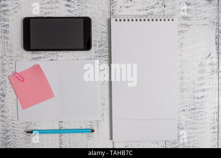 Squared spiral notebook marker smartphone sticky note clip wood background Stock Photo