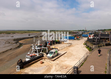 Leigh on Sea fishing boats with shellfish industry area, restaurant, industrial facilities, buildings and narrow channel at low tide. Mud. Jogger Stock Photo