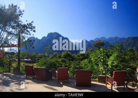 View from a restaurant on row of armchairs and karst hills along Nam Song (Xong) river, Vang Vieng, Laos Stock Photo