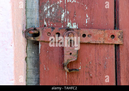 Wooden dirty red blank aged door for backdrop with rusty latch - closeup and detail Stock Photo