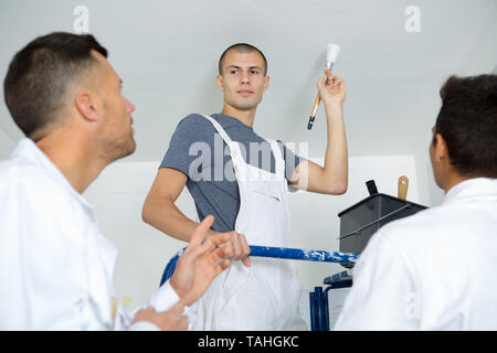 instructor showing apprentices how to paint Stock Photo