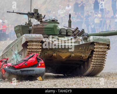 Tank driving over hopeless car vehicle during public military demonstration in Pivka Slovenia M84 MBT driving towards camera front frontal view Stock Photo