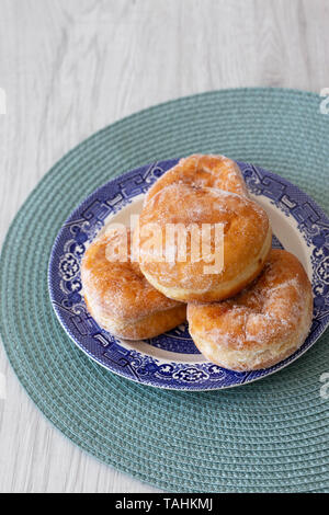 Jam doughnuts on a blue and white plate and green table mat on a grey wood background Stock Photo