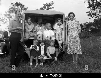 An amusing glimpse of family life in the UK c1950  Mum and Dad pose with children and others packed in the back of a van.  Photo by Tony Henshaw Stock Photo