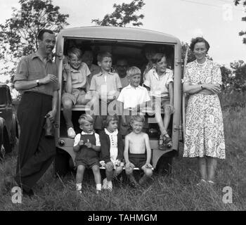 An amusing glimpse of family life in the UK c1950  Mum and Dad pose with children and others packed in the back of a van.  Photo by Tony Henshaw Stock Photo