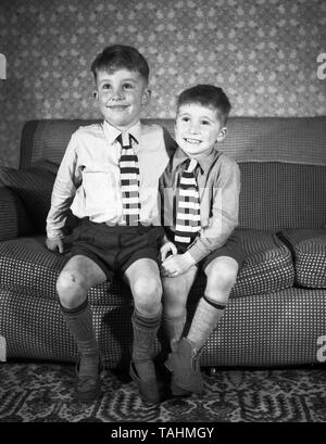 Family Life in the UK c1950  Two smartly dressed young brothers looking happy on a settee  Photo by Tony Henshaw Stock Photo