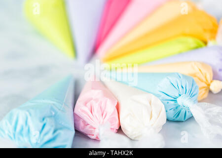 Piping bags with pastel color royal icing to decorate Easter sugar cookies. Stock Photo