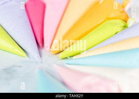 Piping bags with pastel color royal icing to decorate Easter sugar cookies. Stock Photo