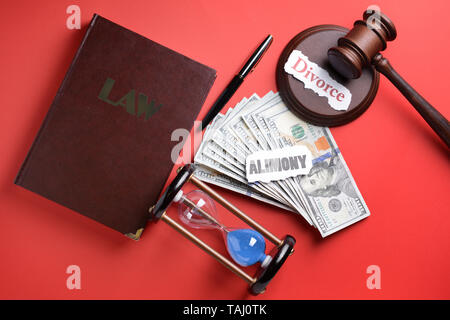 Words ALIMONY and DIVORCE with money, judge gavel, law book and hourglass on color background
