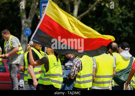 Wiesbaden, Germany. 25th May, 2019. A protester waves a German flag upside down, a symbol of the Reichsburgerbewegung ('Reich Citizens' Movement'), who reject the modern German state. Under 100 right wing protesters marched with yellow vests through Wiesbaden, to protest against the German government. They were confronted by small but loud counter protest. Credit: Michael Debets/Pacific Press/Alamy Live News Stock Photo