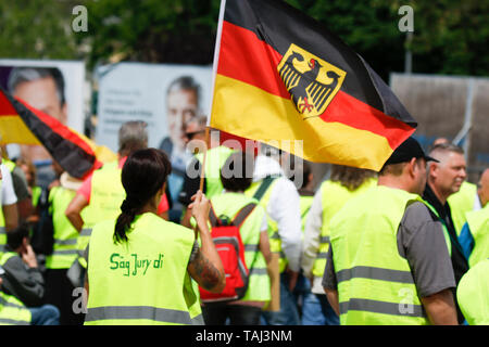 Wiesbaden, Germany. 25th May, 2019. A protester waves a German flag. Under 100 right wing protesters marched with yellow vests through Wiesbaden, to protest against the German government. They were confronted by small but loud counter protest. Credit: Michael Debets/Pacific Press/Alamy Live News Stock Photo