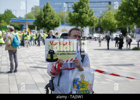 Wiesbaden, Germany. 25th May, 2019. A counter protester holds a sign that reads 'Attention - Brown activities in yellow vests'. Under 100 right wing protesters marched with yellow vests through Wiesbaden, to protest against the German government. They were confronted by small but loud counter protest. Credit: Michael Debets/Pacific Press/Alamy Live News Stock Photo