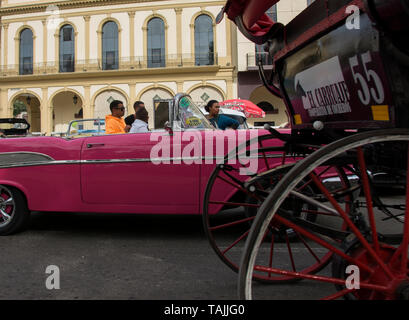Havana, Cuba - A horse-drawn cart passes by a taxi  in front of Hotel Parque Central. Classic American cars from the 1950s, imported before the U.S. e Stock Photo