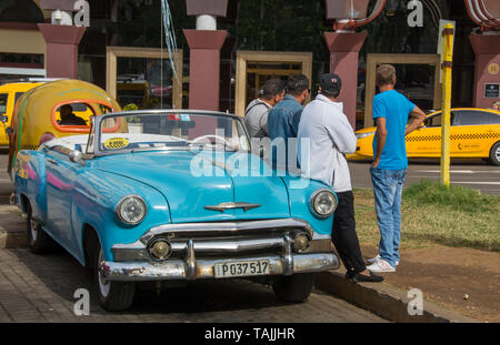 Havana, Cuba - Taxis wait for fares in front of Hotel Parque Central. Classic American cars from the 1950s, imported before the U.S. embargo, are comm Stock Photo