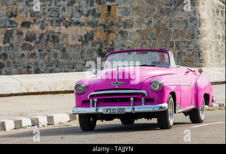Havana, Cuba - A taxi passes in front of Castillo de San Salvador de la Punta on the Malecón road facing Havana Bay. Classic American cars from the 19