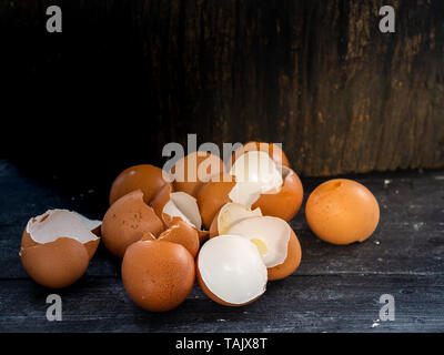 Egg shells on dark wooden plank and log with empty space. Stock Photo