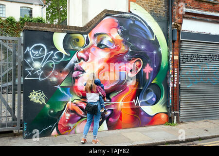 LONDON SPITALFIELDS BRICK LANE AREA WOMAN AND CHILD LOOKING AT COLOURFUL WALL OR STREET ART Stock Photo