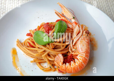 Pasta with scampi sauce, cherry tomatoes and basil. Ready to eat. Spaghetti with scampi, fish food. Stock Photo