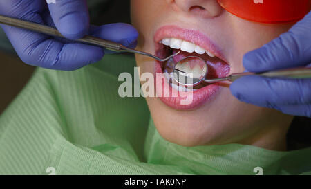 Girl patient in dental clinic. Dentist does routine inspection of teeth. Close-up. Man unrecognizable Stock Photo