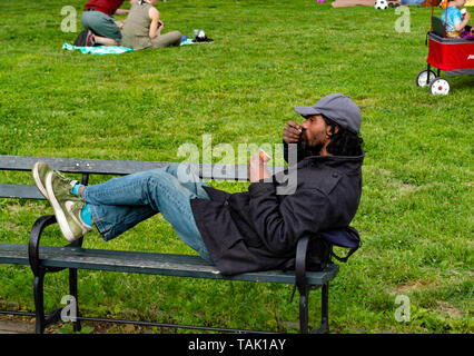 Man is sitting on the bench eating ice cream in Prospect Park, Brooklyn Stock Photo