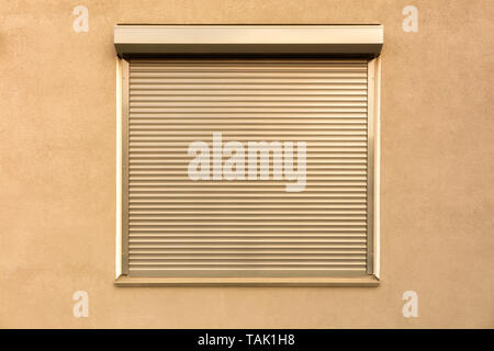 Light brown metal blinds on the window of the facade of the house. Stock Photo