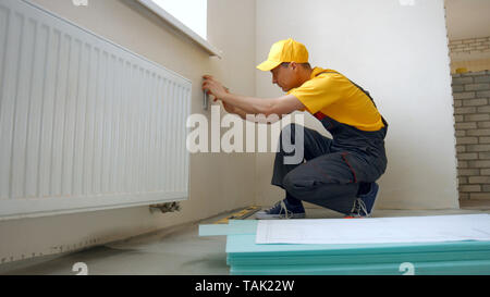 Worker making apartment renovation by project. Builder making a mark on the plan. Stock Photo