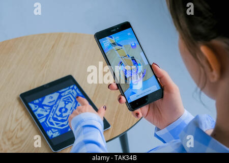 Woman using smartphone with AR app and placing virtual model of building Stock Photo