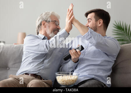 Happy father and son celebrate team win at home Stock Photo