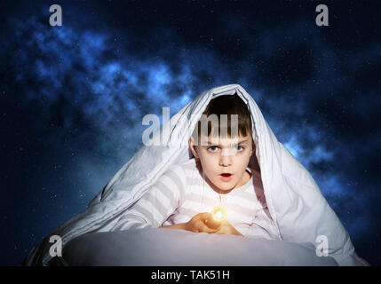 Surprised child hiding under blanket Stock Photo