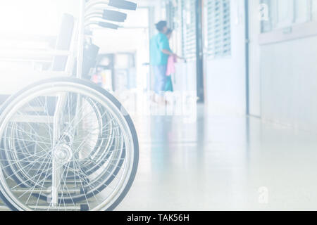Empty wheelchair parked in hospital pathway blurred with patient walk in operation room Stock Photo