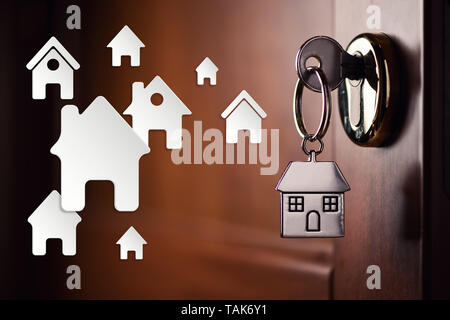 House key on a house shaped silver keyring in the lock of a door Stock Photo