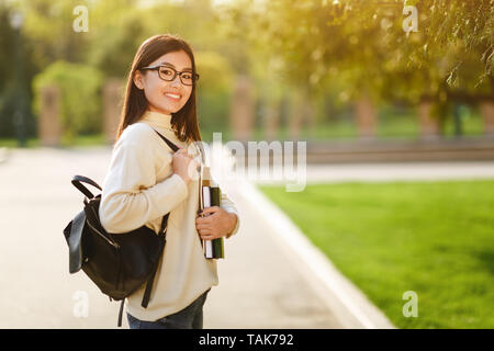 Asian Student Holding Books And Looking At Camera Stock Photo