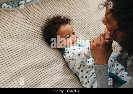 Cute baby boy playing with mother on a bed Stock Photo