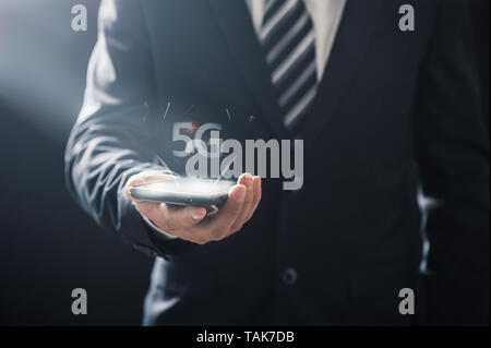Business man using mobile smartphone with 5G icons flow on virtual screen concept. 5G High speed internet network Stock Photo