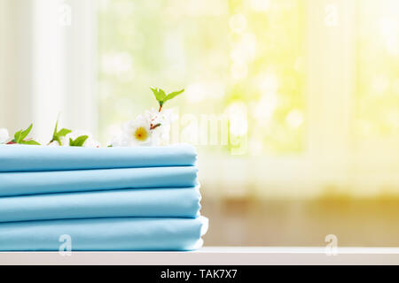 Closeup stack of blue clean bedding on the table. Blurred background. Copy space. Stock Photo