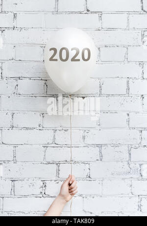White balloon with gold 2020 numbers in woman hand Stock Photo